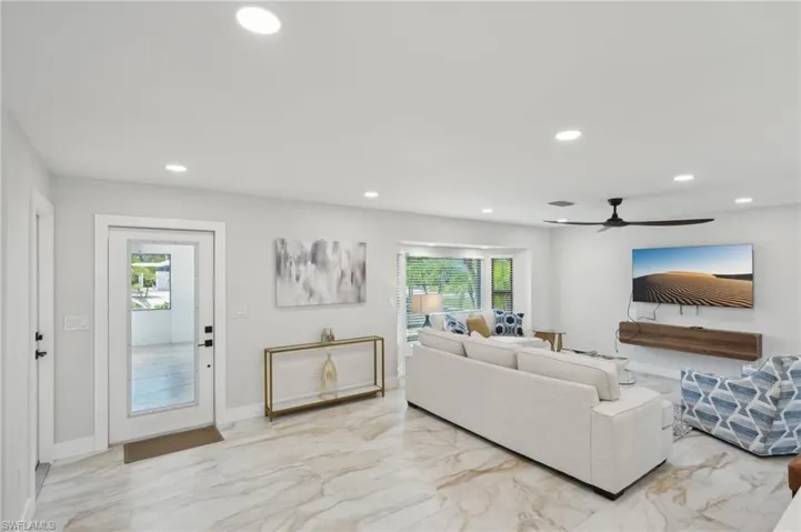 Living area featuring light marble finish flooring, recessed lighting, plenty of natural light, ceiling fan, and baseboards