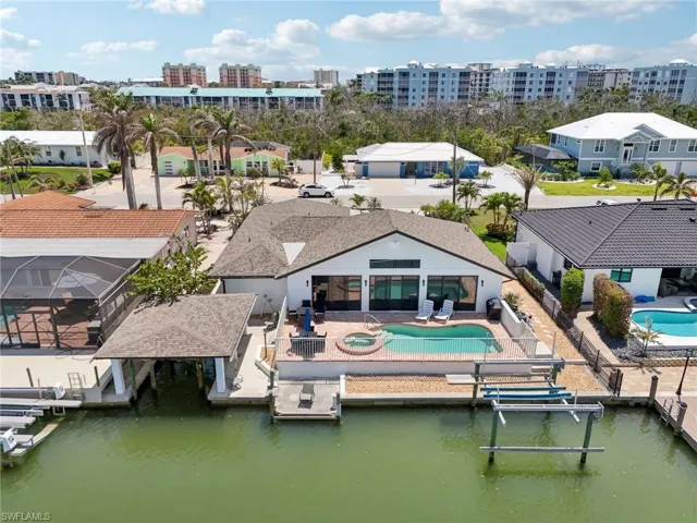 Rear view of house with an outdoor pool, a fenced backyard, a patio, and a water view