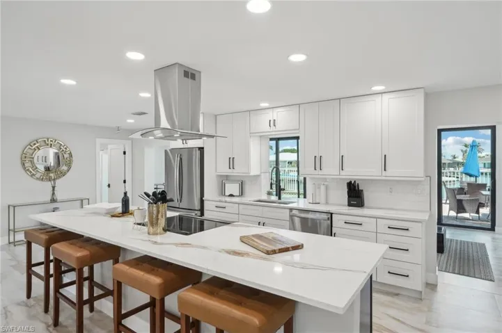 Kitchen with stainless steel appliances, a sink, island range hood, recessed lighting, and a kitchen breakfast bar
