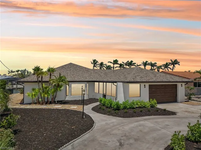 View of front of property with stucco siding, driveway, an attached garage, and roof with shingles
