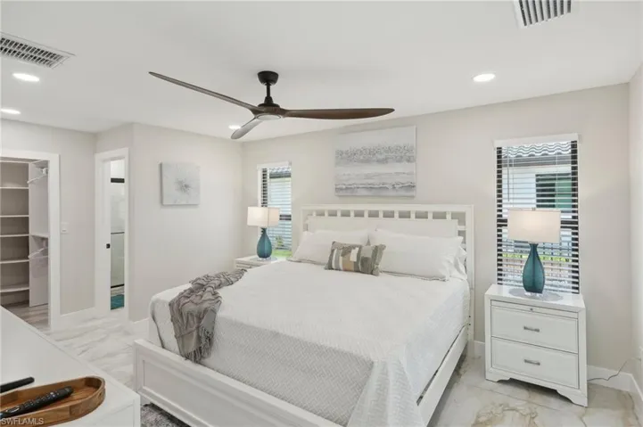 Bedroom featuring light marble finish flooring, a walk in closet, recessed lighting, baseboards, and ceiling fan