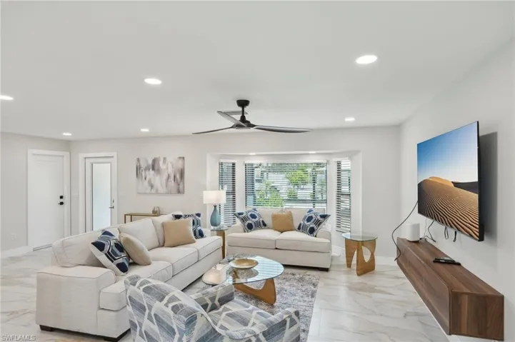 Living area with light marble finish flooring, recessed lighting, ceiling fan, and baseboards