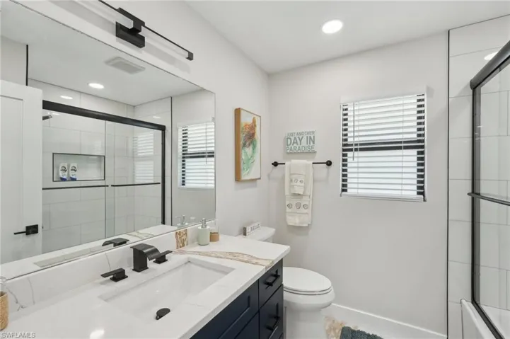 Full bath featuring a shower with door, toilet, vanity, and recessed lighting