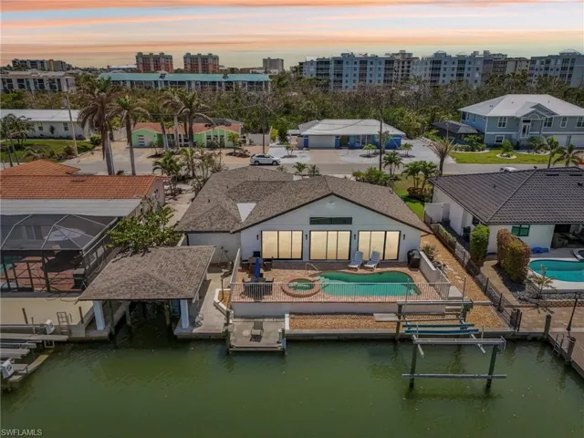 Rear view of house featuring a fenced backyard, a water view, a pool with connected hot tub, and a patio