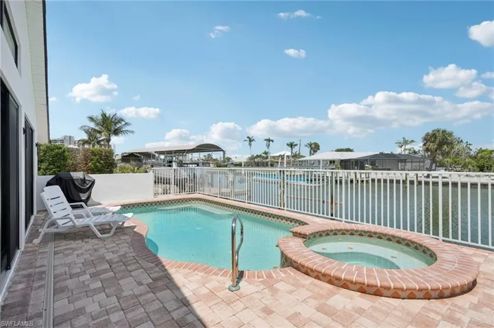 View of swimming pool with a fenced backyard, a patio area, a water view, grilling area, and a pool with connected hot tub