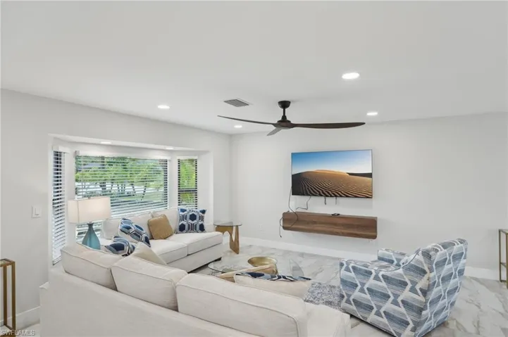 Living area with marble look tiles, ceiling fan, recessed lighting, and baseboards