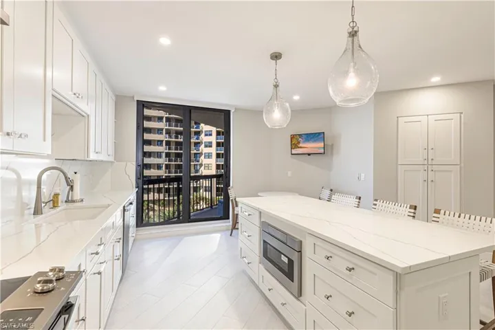 Kitchen featuring appliances with stainless steel finishes, sink, decorative light fixtures, white cabinets, and a breakfast bar area