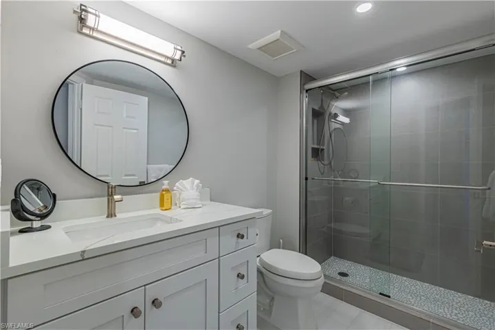Bathroom with tile patterned flooring, vanity, toilet, and a shower with door