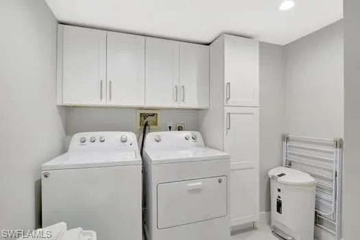 Laundry area with washer and clothes dryer, cabinet space, and radiator