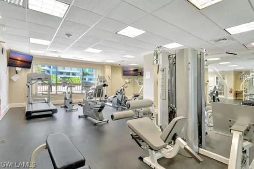 Workout area featuring a paneled ceiling, visible vents, and baseboards