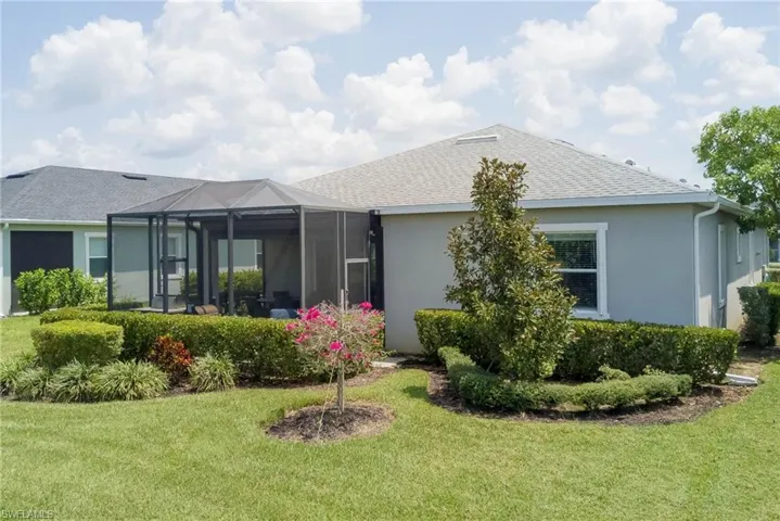 Back of house featuring a yard, a sunroom, glass enclosure, and roof with shingles