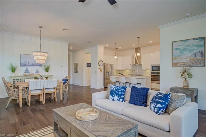 Living room featuring dark wood-style flooring, ornamental molding, a chandelier, recessed lighting, and ceiling fan