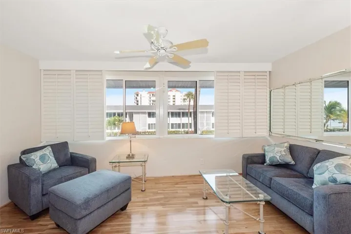 Den area with wood finished floors, ceiling fan and plantation shutters