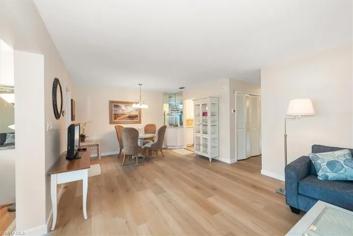 Living room featuring light wood finished floors and baseboards - facing dining area and kitchen