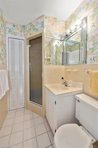 Full bathroom with tile walls, vanity, a stall shower, and tasteful backsplash
