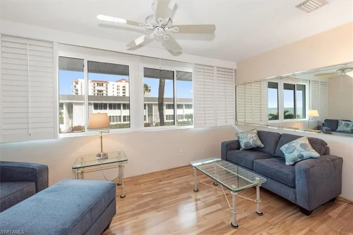 Den with a ceiling fan, wood finished floors, and plenty of natural light