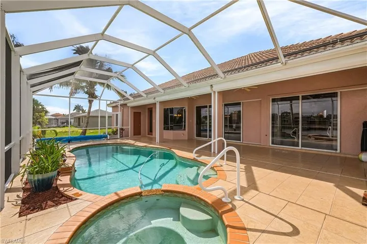 View of a pool with connected spa and screened lanai