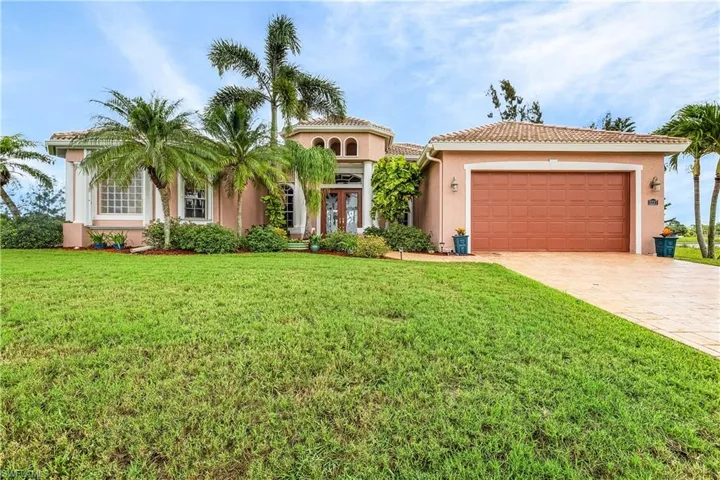 Mediterranean / spanish home with driveway, a garage, stucco siding, a front lawn, and a tiled roof