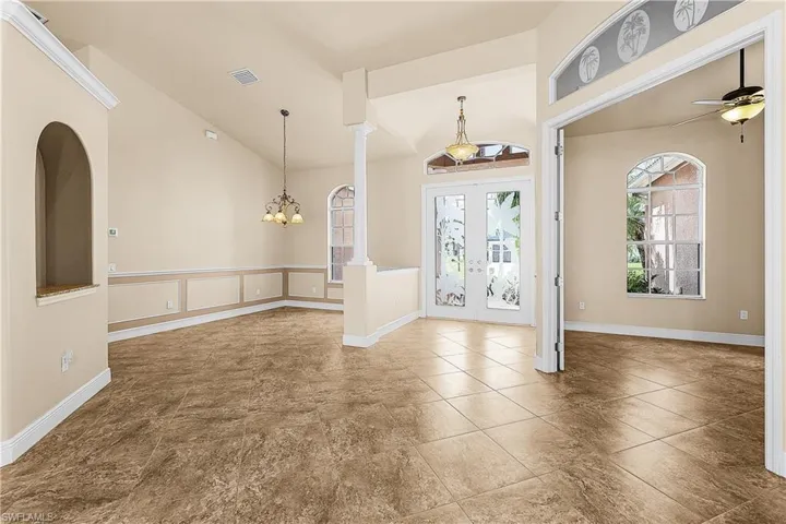 Foyer entrance with plenty of natural light, french doors, ceiling fan, ornate columns, and high vaulted ceiling