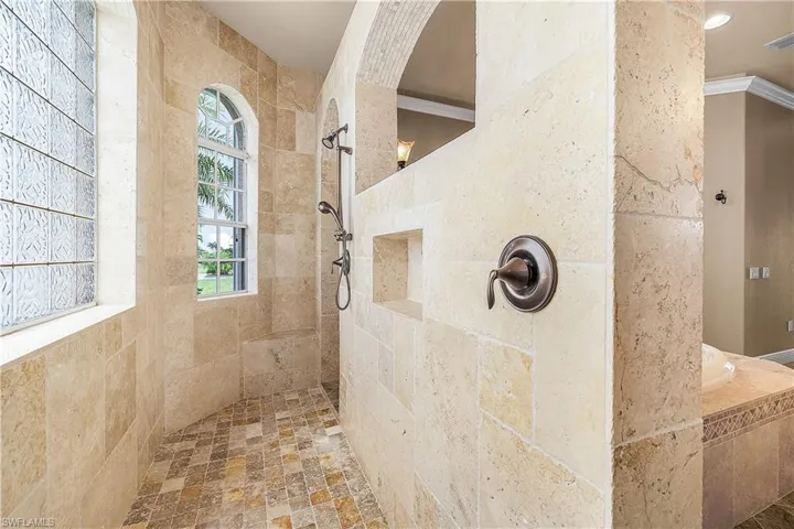 Primary bathroom with walk in shower, crown molding, and tile flooring