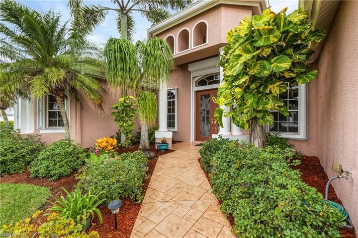 Entrance to property with stucco siding and landscaping