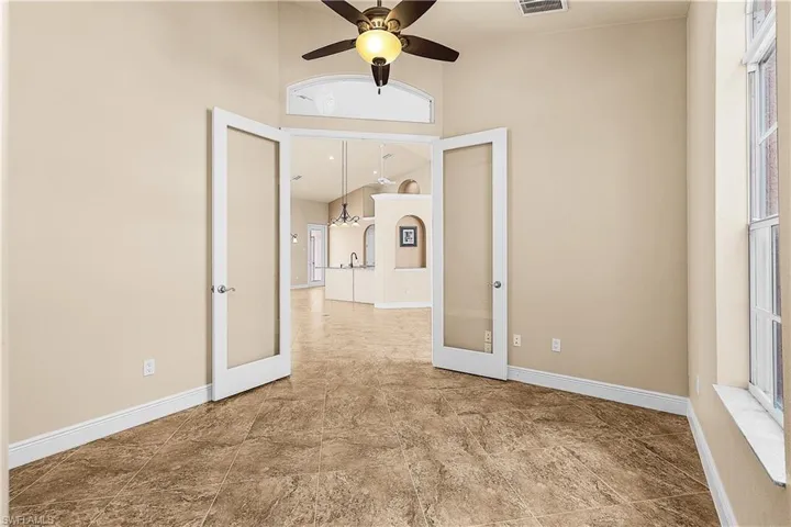 Den and/or office with french doors, a high ceiling, and ceiling fan