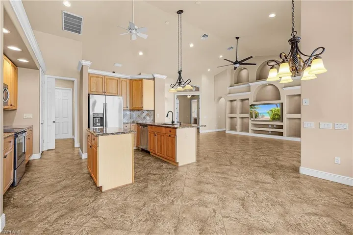 Kitchen with a ceiling fan, appliances with stainless steel finishes, open floor plan, built in features, and a kitchen island