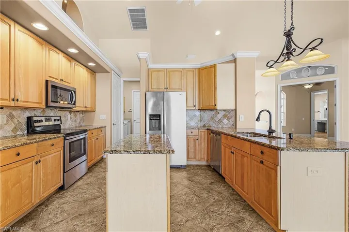 Kitchen with appliances with stainless steel finishes, a kitchen island, dark stone countertops, and recessed lighting