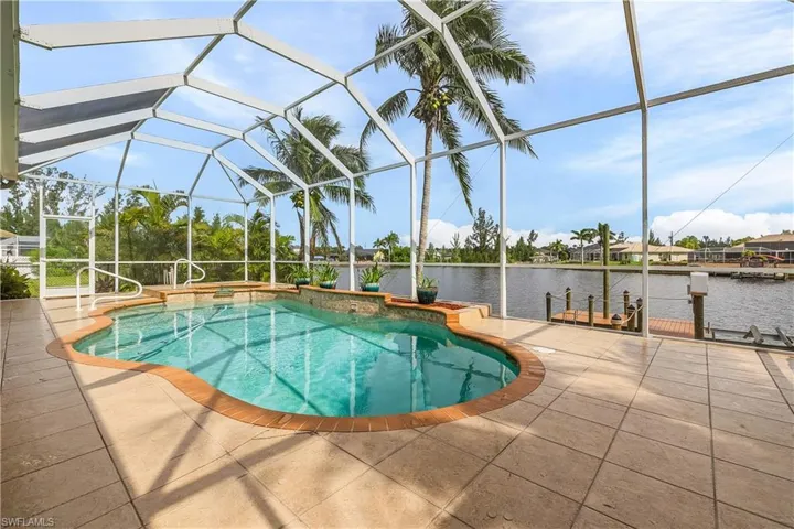 Outdoor pool and spa featuring a patio area, a water view, and a screened lanai