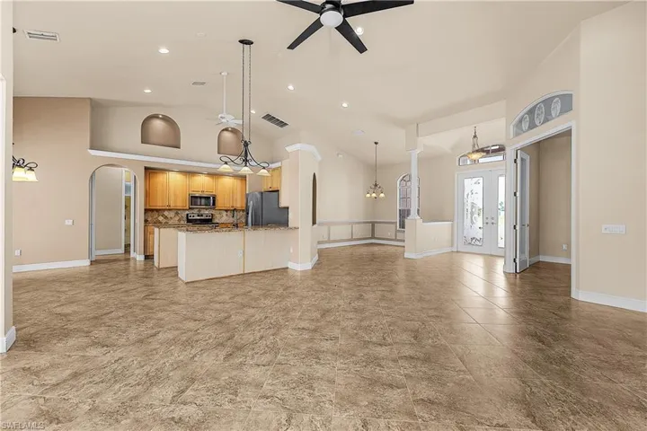 Living room with arched walkways, a ceiling fan, high vaulted ceiling, a chandelier, and recessed lighting