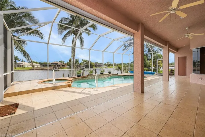View of swimming pool featuring a patio area, ceiling fan, a spa, and a screened lanai