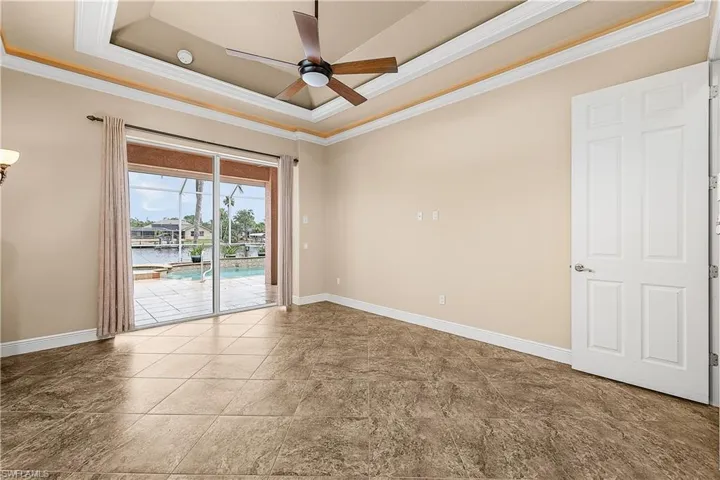 Primary bedroom with crown molding, a tray ceiling, and ceiling fan