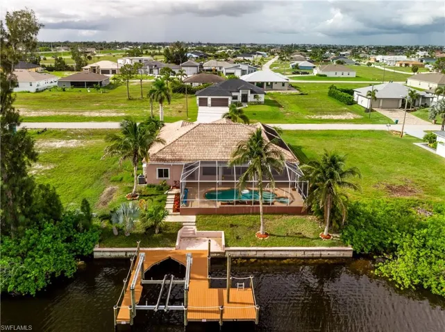 Aerial perspective of property featuring gulf access, a boat dock, and a pool and spa area