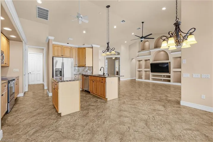 Kitchen with a ceiling fan, stainless steel appliances, open floor plan, built in features, and recessed lighting