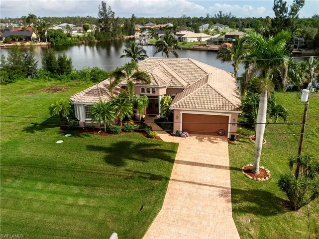 Mediterranean / spanish house featuring a tiled roof, a water view, stucco siding, and an attached garage