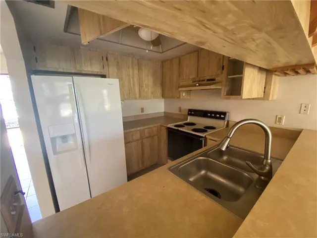 Kitchen featuring white appliances, sink, and a wealth of natural light