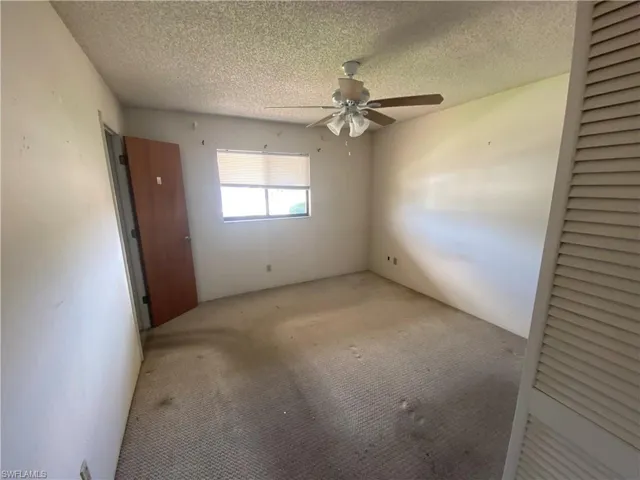 Carpeted empty room featuring ceiling fan and a textured ceiling