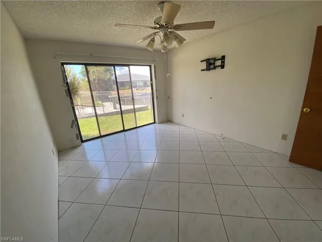 Unfurnished room featuring a textured ceiling, ceiling fan, and light tile flooring