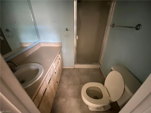 Bathroom with tile flooring, walk in shower, vanity, and toilet