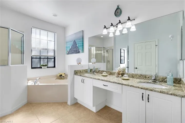 Full bathroom featuring a shower stall, a bath, double vanity, and light tile patterned floors
