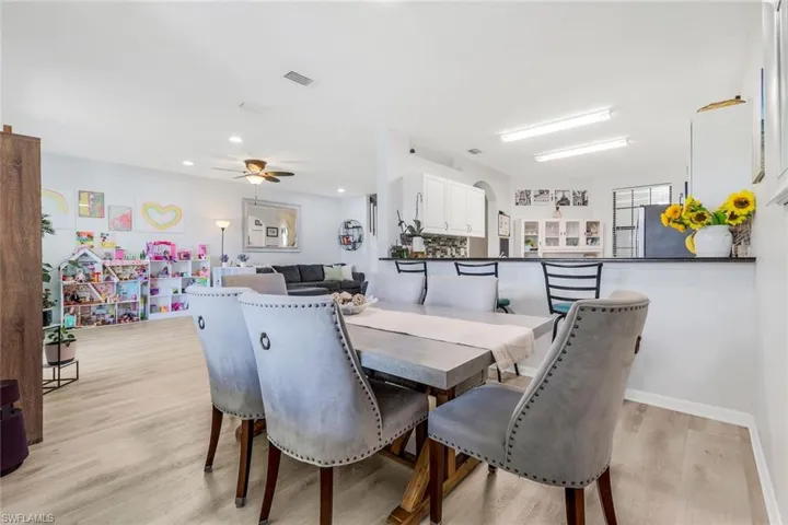 Dining space featuring light wood finished floors, arched walkways, a ceiling fan, and recessed lighting