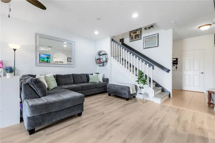 Living room featuring light wood-type flooring, stairway, recessed lighting, and ceiling fan