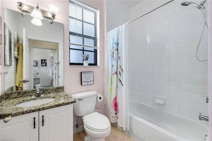 Bathroom with vanity, shower / bath combo with shower curtain, and light tile patterned flooring