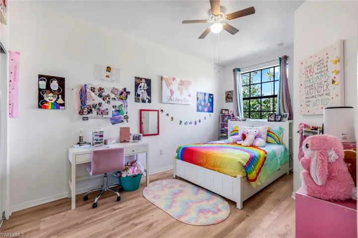 Bedroom with wood finished floors, ceiling fan, and an office area