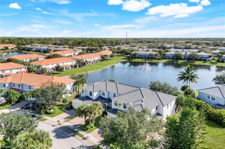 Aerial perspective of suburban area with a nearby body of water and a tree filled landscape