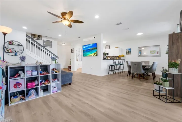 Living area featuring light wood-style flooring, a ceiling fan, recessed lighting, stairway, and a barn door