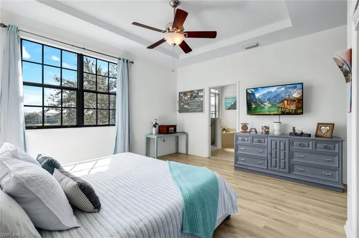 Bedroom featuring a tray ceiling, light wood finished floors, and ceiling fan