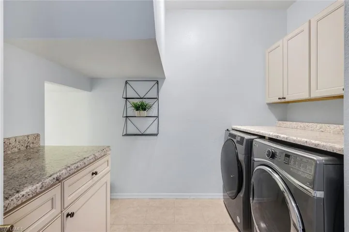 Washroom with cabinet space, independent washer and dryer, and light tile patterned floors