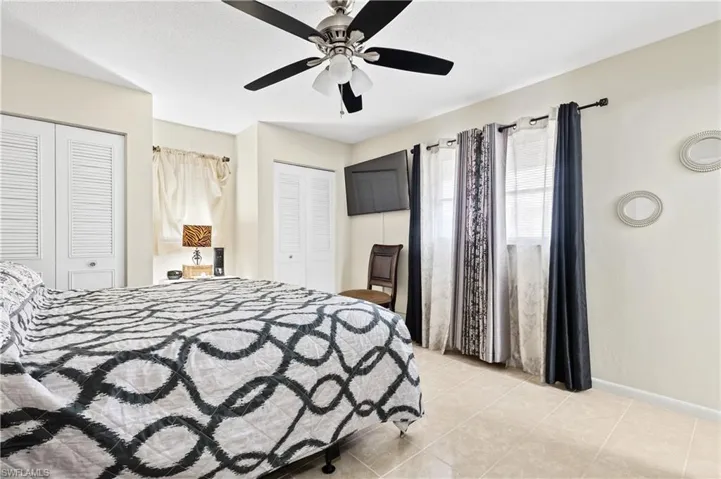 Bedroom with two closets, ceiling fan, and light tile patterned floors