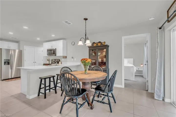 Tiled dining space featuring sink and a notable chandelier